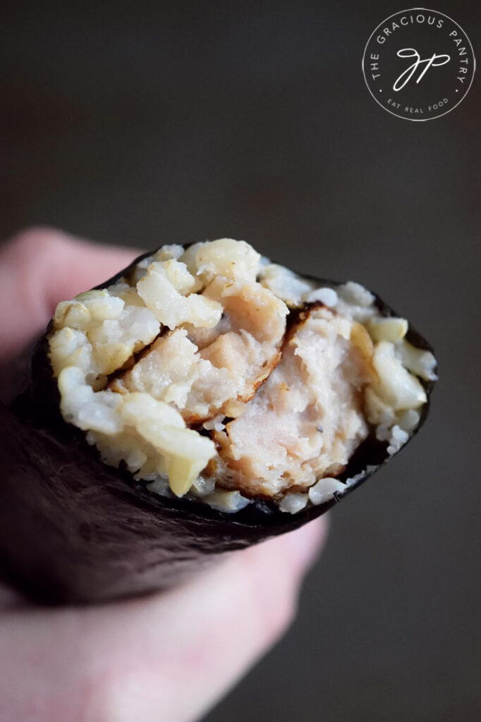 A roll of gimbap with a bite taken off. You can see the sausage and rice inside the nori.