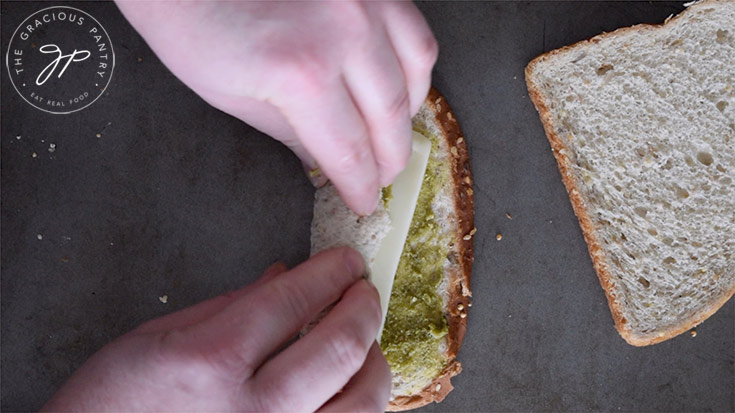 Rolling up the slice of bread with cheese like a rug.