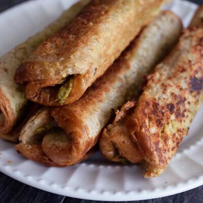 Several Grilled Cheese Roll Ups With Pesto on a serving plate.