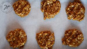 Flattened Peanut Butter Oatmeal Cookie dough scoops on a cookie sheet.