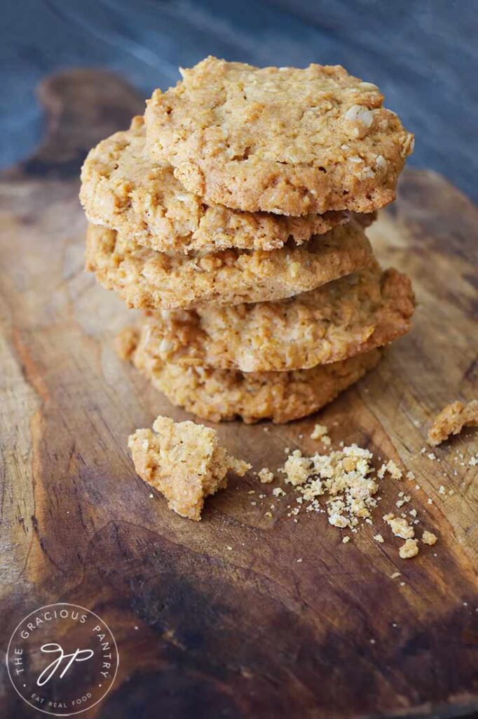 A stack of five Peanut Butter Oatmeal Cookies sit on a wooden cutting board.