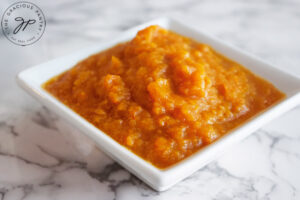 The finished persimmon pulp sitting in a white, square dish.