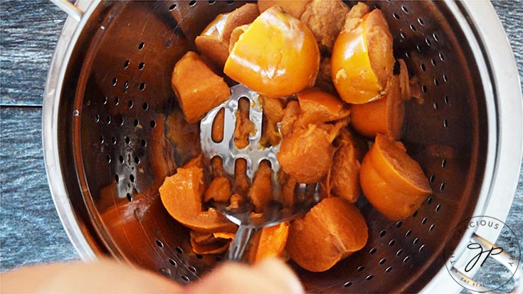 Mashing the persimmons with a potato masher to make the persimmon pulp.