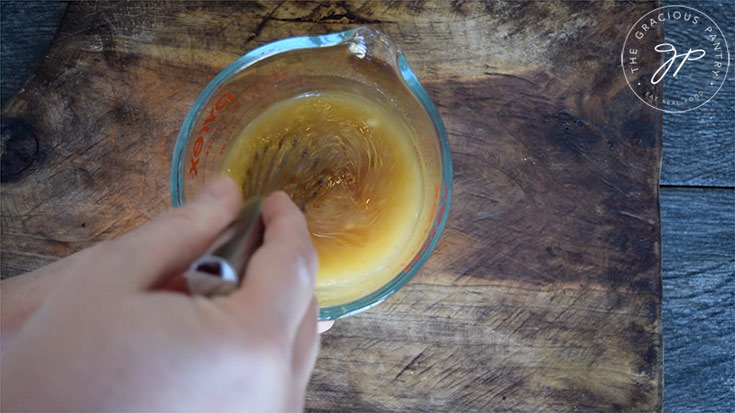 Whisking the gravy ingredients together in a measuring cup.