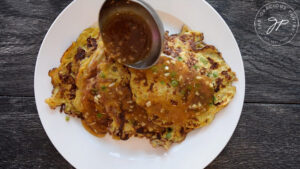 Ladling gravy over the finished egg foo young.