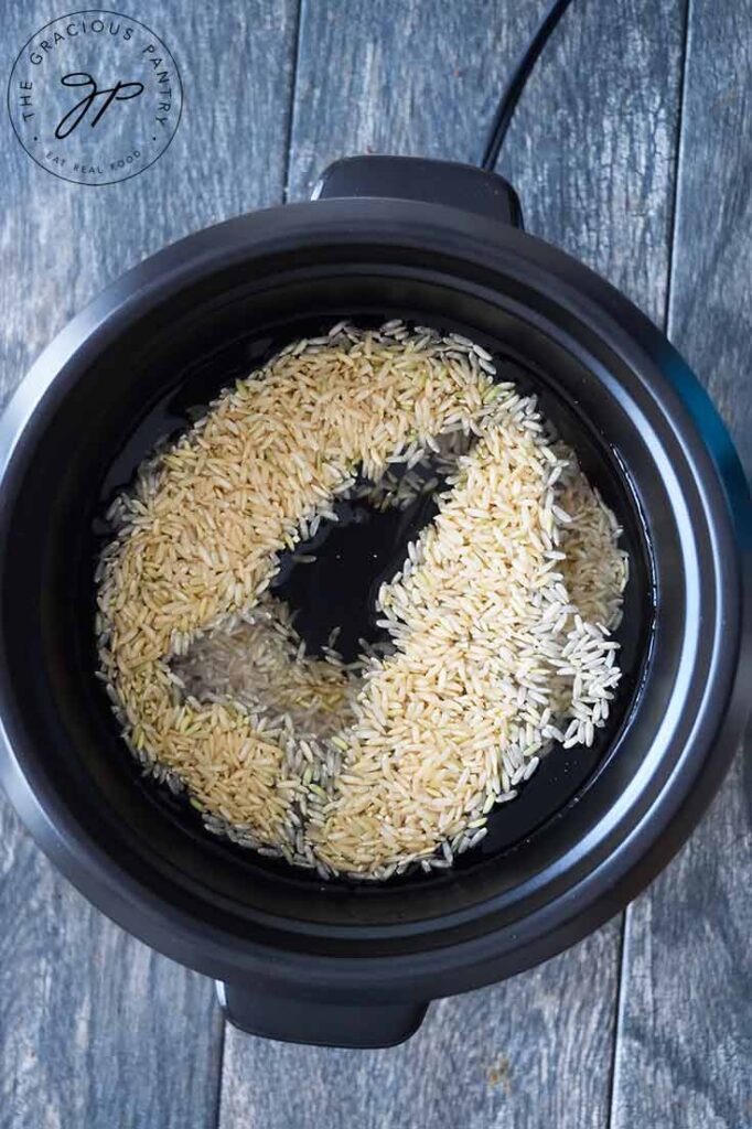 Dry rice in water in a rice cooker, ready to cook.