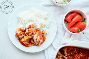 An overhead view of cheesy baked meatballs served with a side of rice.