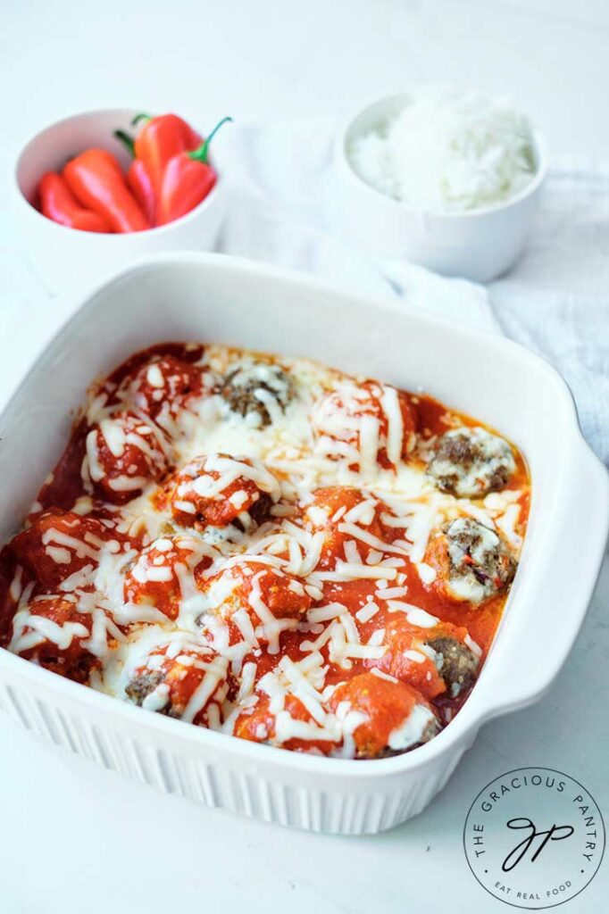 Finished Cheesy Baked Meatballs just out of the oven and still in a white casserole dish.