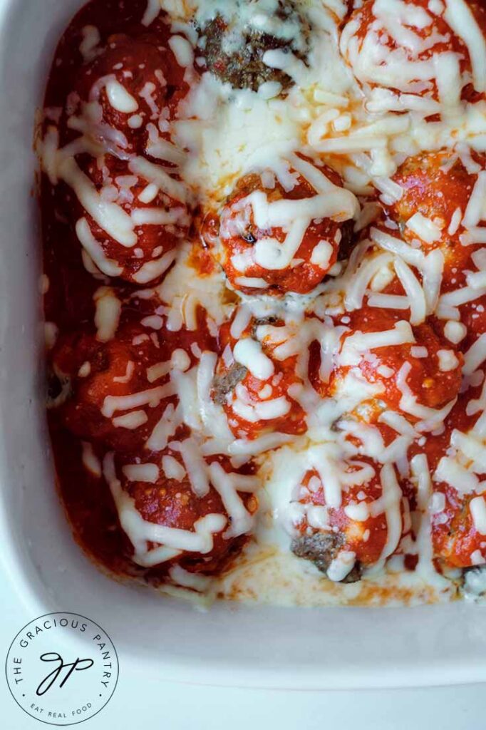 Overhead view looking down into a white casserole dish filled with this Cheesy Baked Meatballs Recipe.