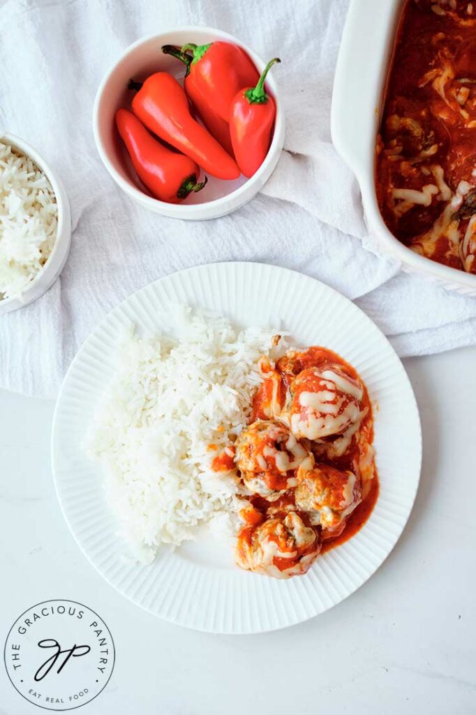 Cheesy Baked Meatballs plated with a side of rice on a white plate.