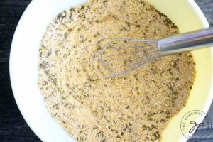 Dry ingredients for this low carb drop biscuits recipe combined in a mixing bowl. A whisk rests inside the bowl on the right.