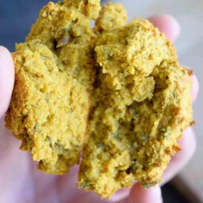 A hand holding a drop biscuit, broken in half to show the inside.