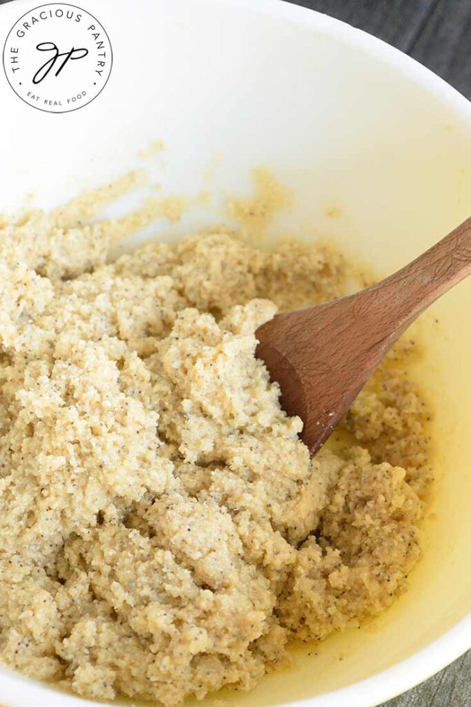 Gluten Free Lemon Poppy Seed Muffins dough in a mixing bowl with a wooden spoon.