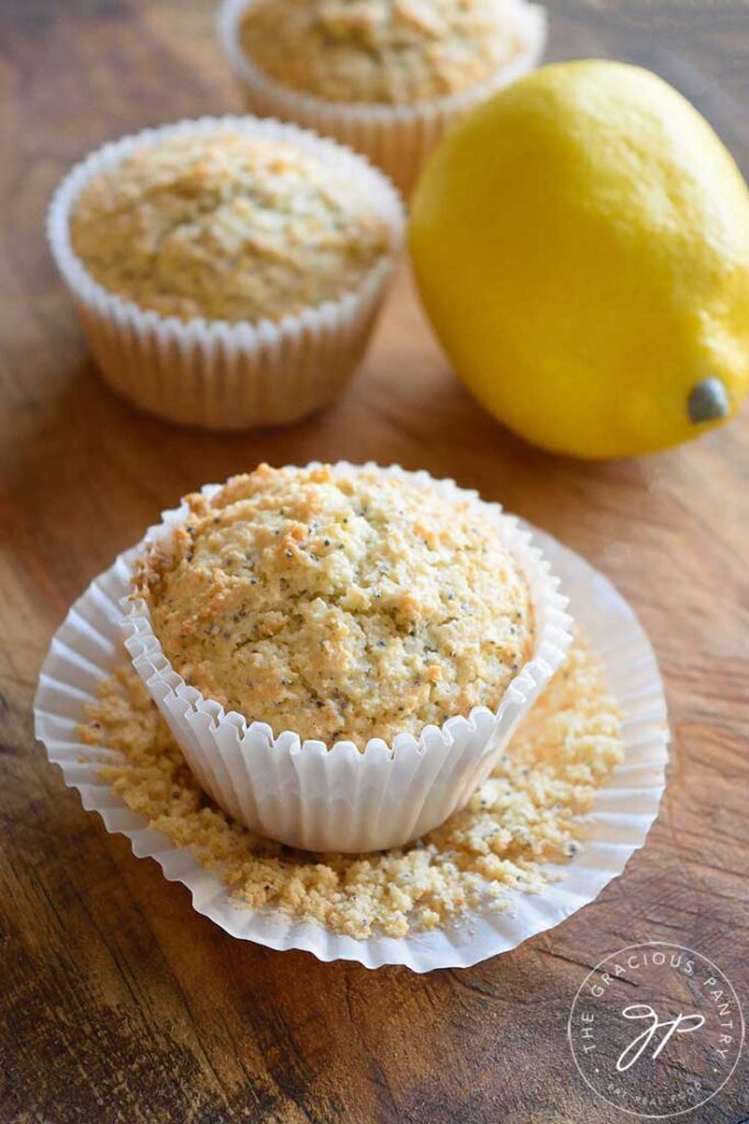 Single Gluten Free Lemon Poppy Seed Muffins on a cutting board with a whole lemon next to them.