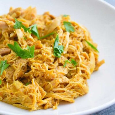 A white bowl filled with this Honey Mustard Chicken and topped with some fresh, chopped herbs.