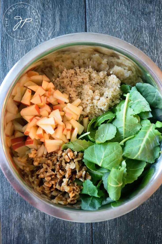 The individual ingredients for this Kale Quinoa Salad separated for easy viewing in a mixing bowl.