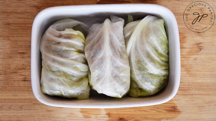 Three Mexican Cabbage Rolls, rolled up and placed tightly in a small casserole dish.