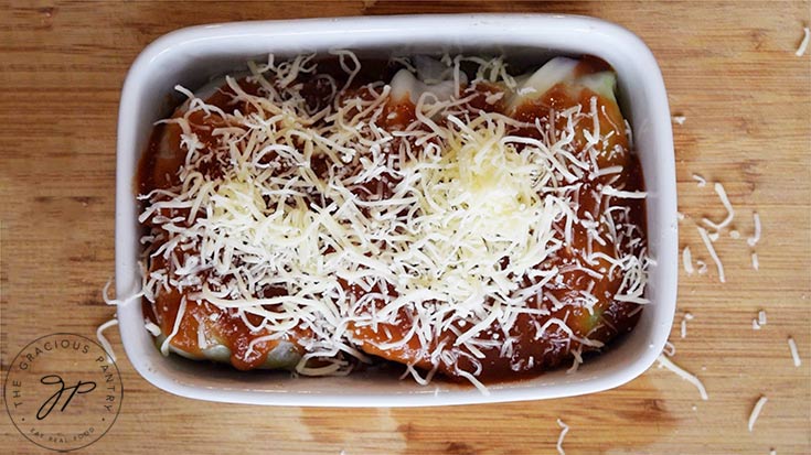 Cheese sprinkled over the top of the Mexican cabbage rolls, and they are ready for the oven.