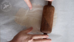 Rolling the dough very thing between parchment paper.