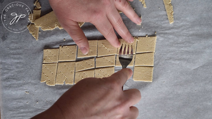 Poking the cut crackers with a fork for even baking.