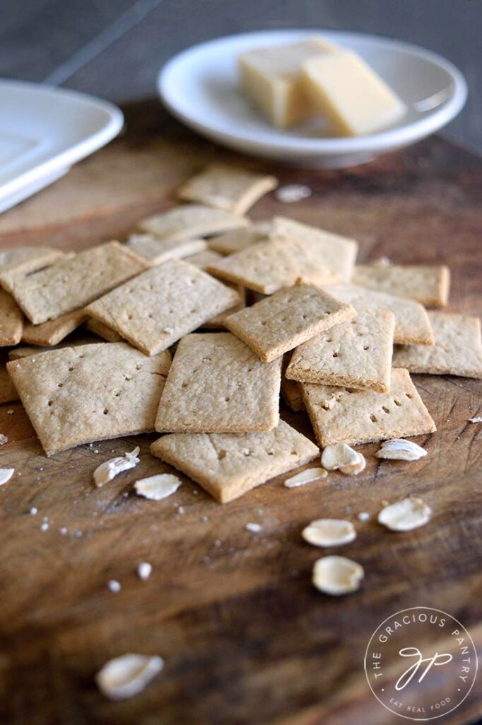 And up close view of the oat crackers on a cutting board. A few whole oats are scattered around them.