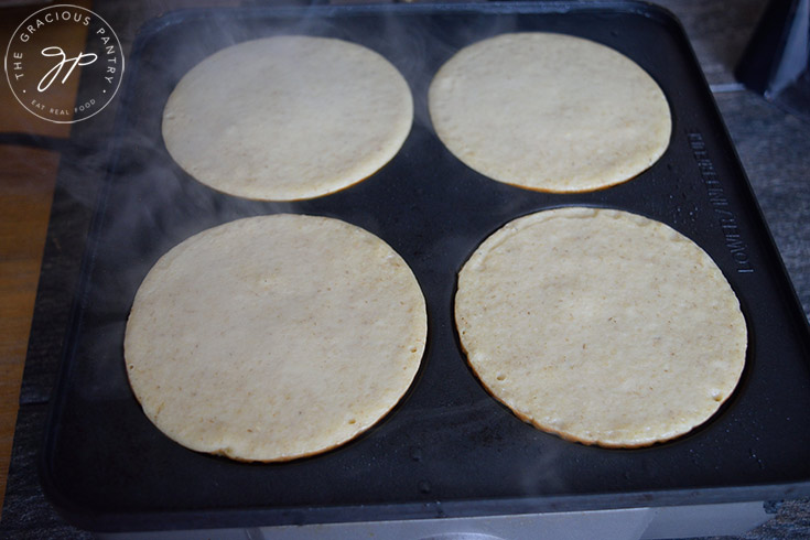 Pancakes cooking on a griddle.