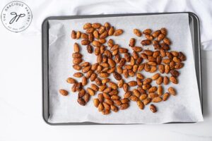 The prepared almonds spread out on a baking sheet, lined with parchment paper.