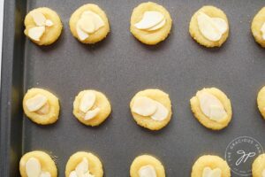 Almond cookies lined up on a cookie sheet, ready to go into the oven for baking.