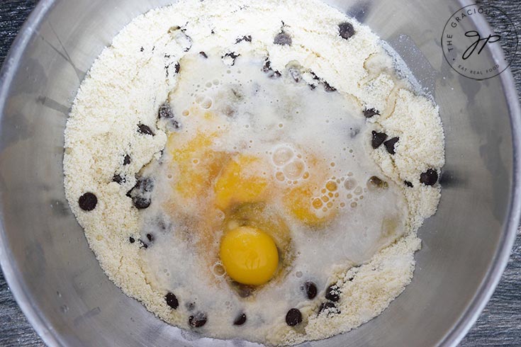 Adding the wet ingredients to the mixing bowl of dry ingredients in this almond flour muffins recipe.