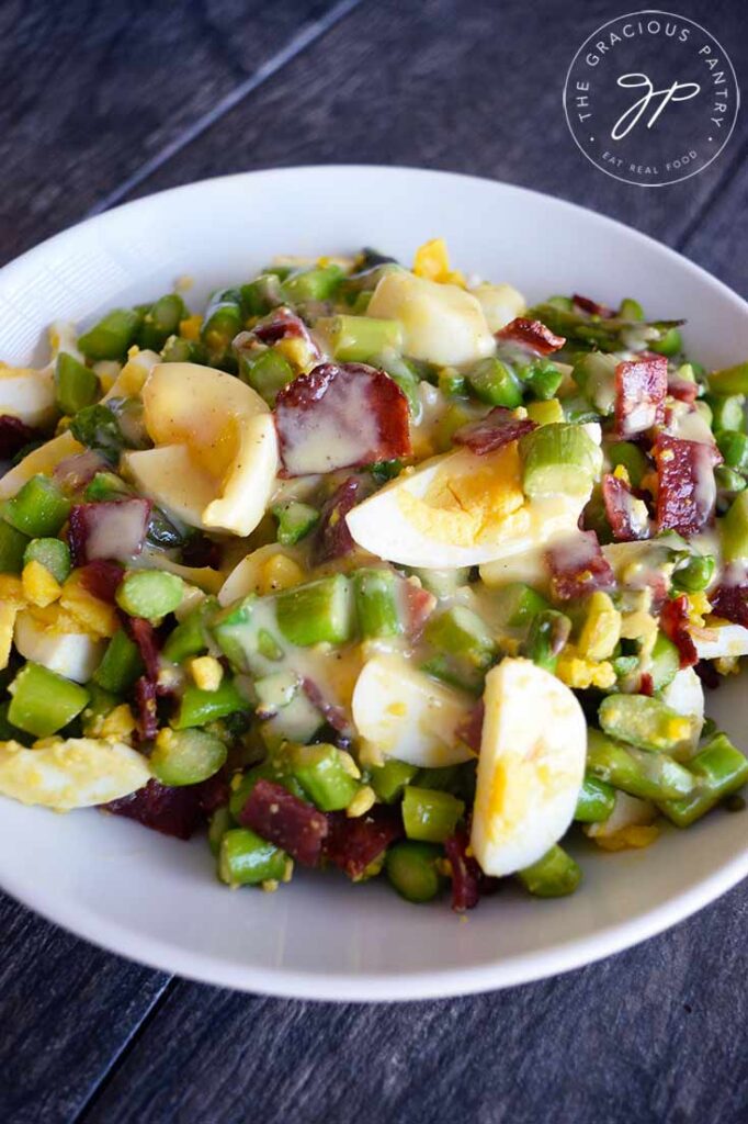 Asparagus Salad served in a white bowl with vinaigrette over the top.