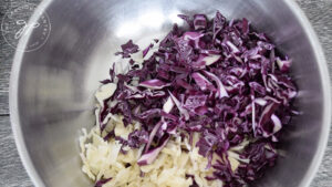 The green and purple cabbage, cut and ready to mix in a mixing bowl.