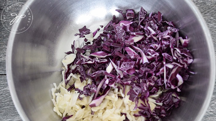 The green and purple cabbage, cut and ready to mix in a mixing bowl.