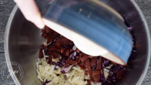 Pouring the dressing into the mixing bowl with the cabbage.
