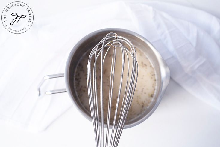 All the ingredients whisked together in a metal bowl. A whisk sits over the top of the bowl.