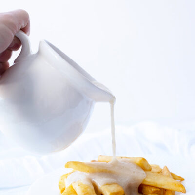 Chicken Broth Gravy being poured over french fries.