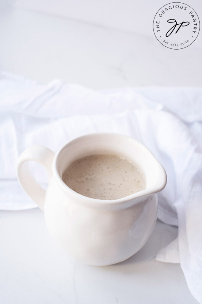 A white pitcher filled with Chicken Broth Gravy.