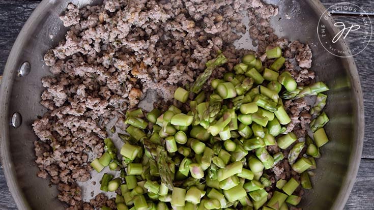 Adding the asparagus to the skillet for this Ground Turkey Skillet Dinner Recipe.