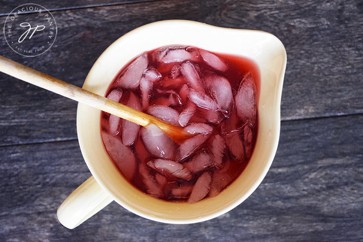 The steeped Hibiscus Lemonade in a pitcher with ice.