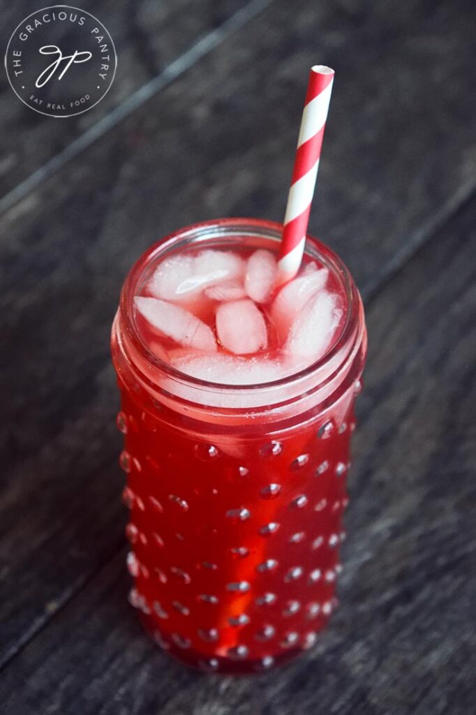The finished Hibiscus Lemonade in a glass cup with a red and white straw.