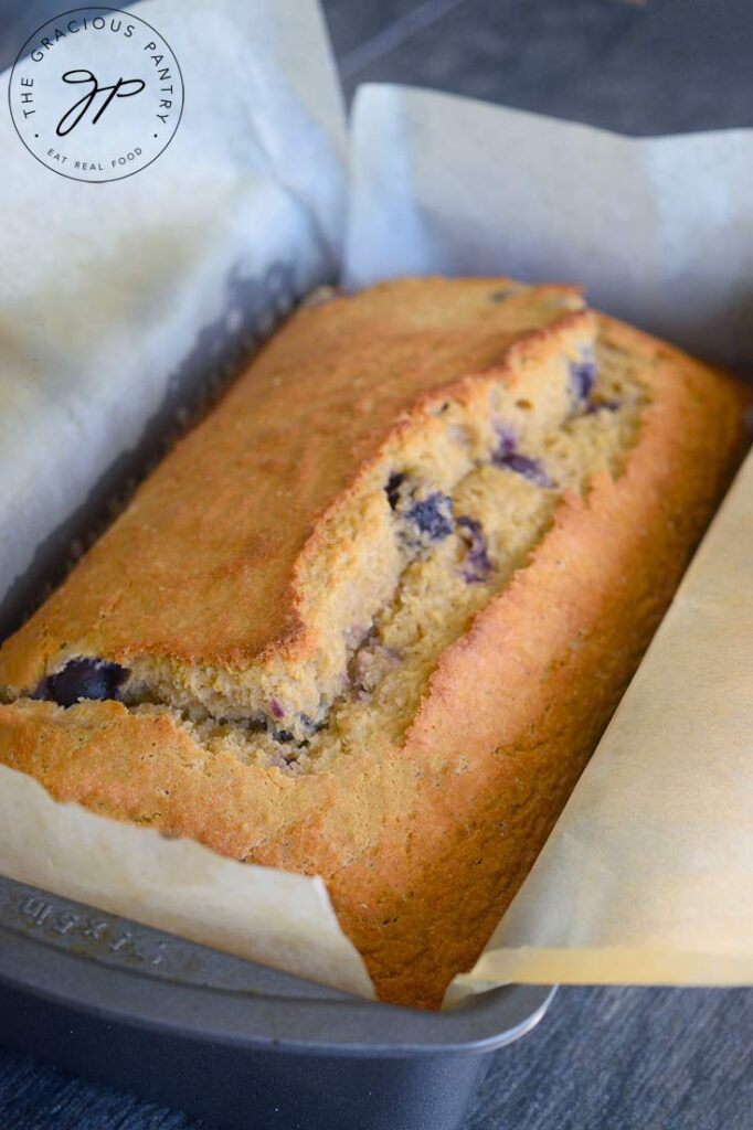 A side view of this Lemon Blueberry Bread in a parchment lined loaf pan.