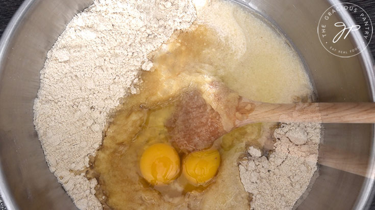 The wet ingredients added to the flour mix in a mixing bowl.