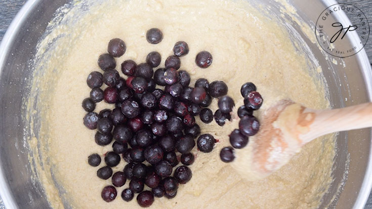 The blueberries added to the batter in a mixing bowl.