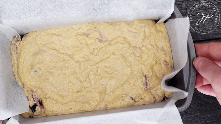 Tapping the loaf pan on the counter top to settle the batter in the pan.