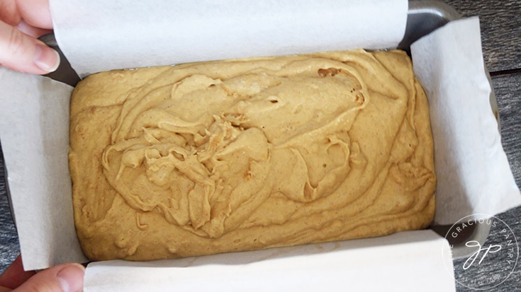 Tapping the loaf pan on the counter to settle the Peanut Butter Bread batter in the loaf pan.