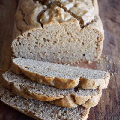 A loaf of Peanut Butter Bread with three slices sliced off one end, sitting on a cutting board.