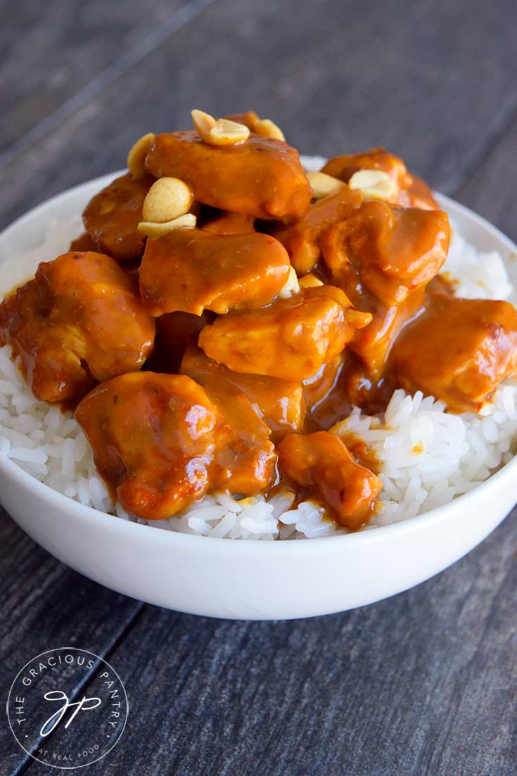 Peanut butter chicken in a white bowl in a bed of rice.