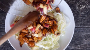 Topping the cabbage with the sweet potato mixture to finish this Roasted Potato Salad before serving.