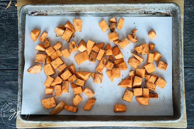 The chopped and seasoned sheet potatoes on a baking pan.