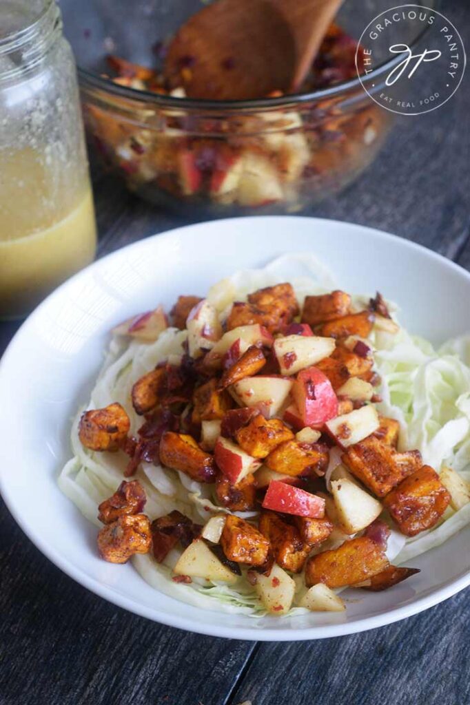 A front view of this Roasted Potato Salad on a table with dressing and a second bowl sitting behind it.