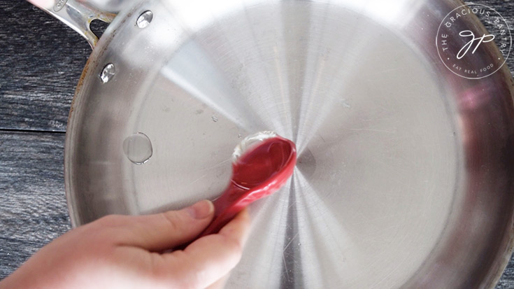 Adding oil to a large skillet.